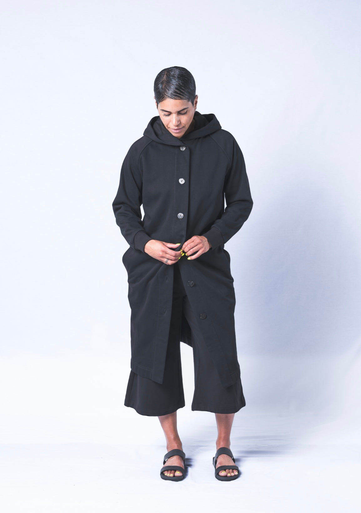 Somewhere between a cardigan and a coat...Its a Coatigan! Hand-picked black cotton poly blend fabric ensures lasting comfort no matter how many times you wash it. Features oversized hood for extra comfort and pearl button closure. Sizes Small-Large available.
